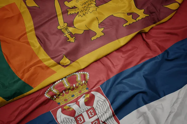 waving colorful flag of serbia and national flag of sri lanka.