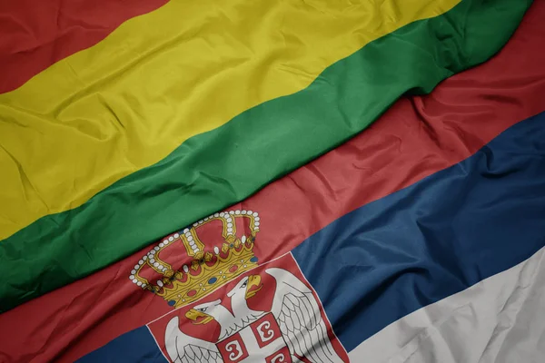 waving colorful flag of serbia and national flag of bolivia.