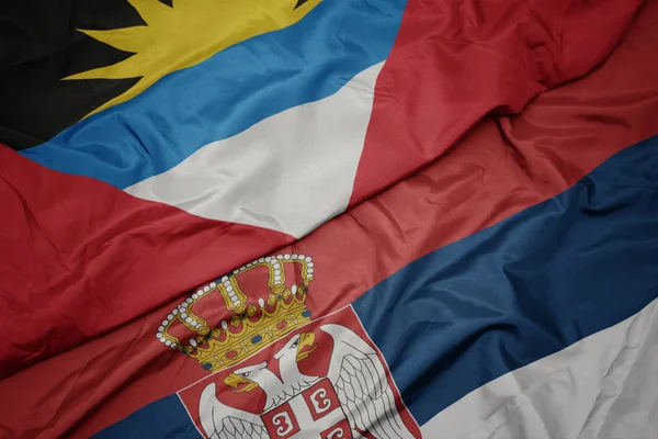 waving colorful flag of serbia and national flag of antigua and barbuda.