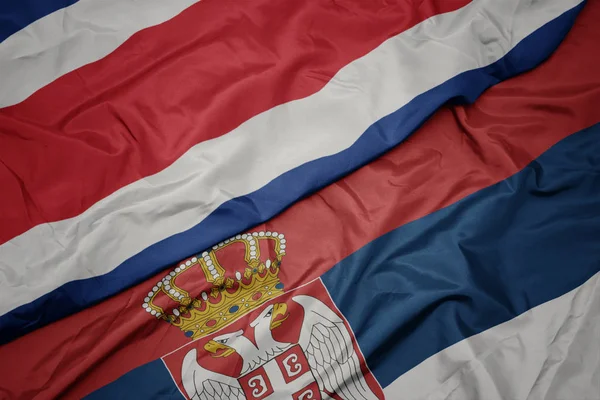 waving colorful flag of serbia and national flag of costa rica.