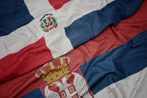 waving colorful flag of serbia and national flag of dominican republic.