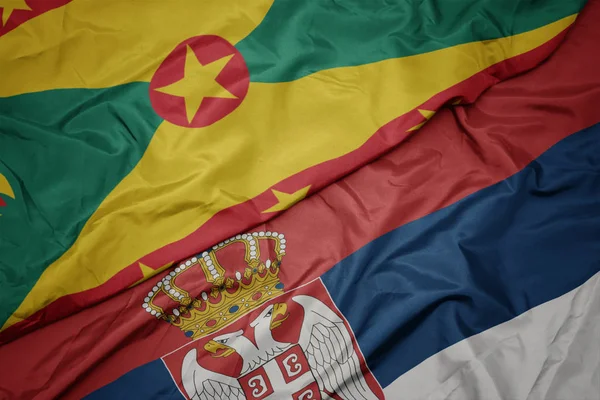 waving colorful flag of serbia and national flag of grenada.