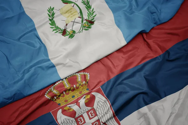 waving colorful flag of serbia and national flag of guatemala.