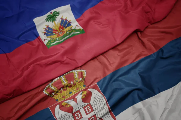 Agitant le drapeau coloré de la serbie et le drapeau national de haiti . — Photo