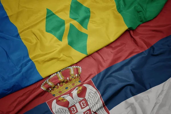 Ondeando colorida bandera de serbia y bandera nacional de santo vincent y las granadinas . — Foto de Stock