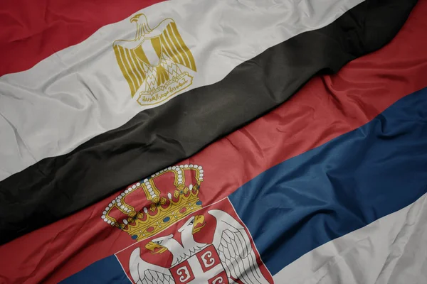 waving colorful flag of serbia and national flag of egypt .