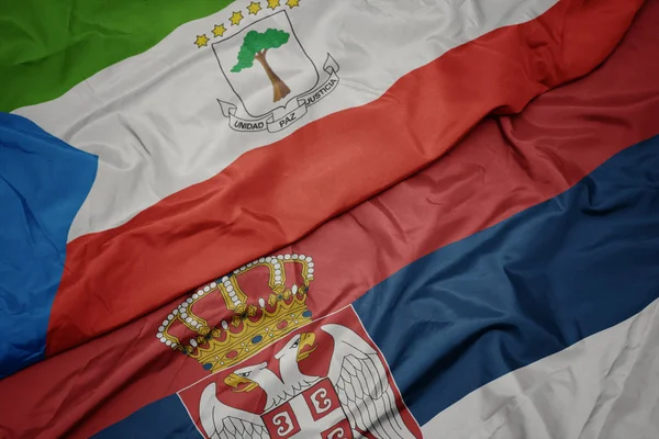 waving colorful flag of serbia and national flag of equatorial guinea.