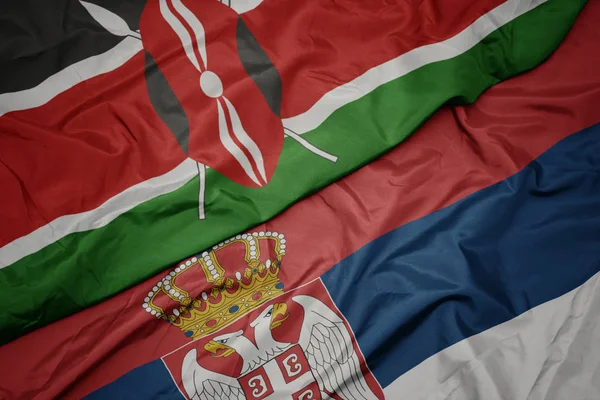waving colorful flag of serbia and national flag of kenya.