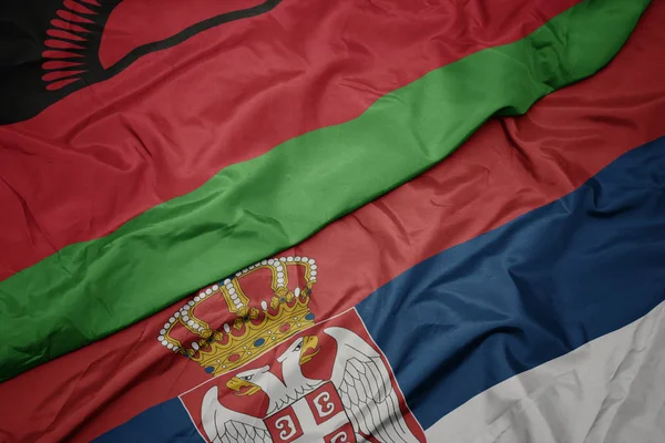waving colorful flag of serbia and national flag of malawi.