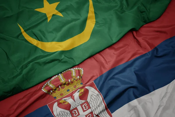 waving colorful flag of serbia and national flag of mauritania.