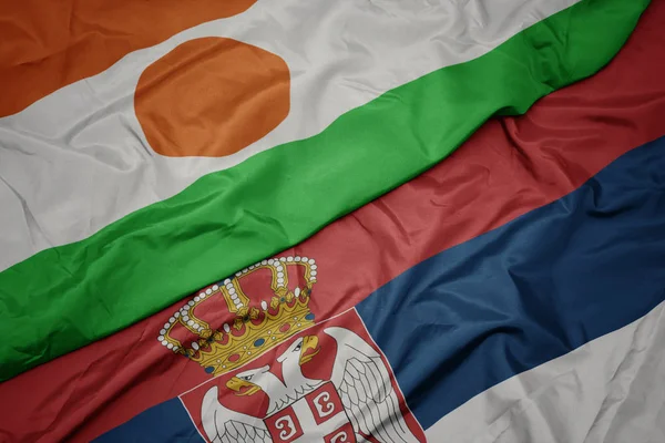 waving colorful flag of serbia and national flag of niger.