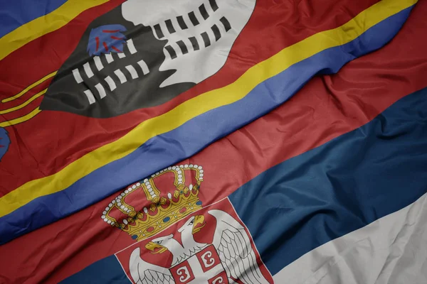 waving colorful flag of serbia and national flag of swaziland.