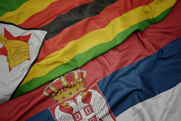 Размахивая красочным флагом Сербии и национальным флагом Зимбабве . — стоковое фото