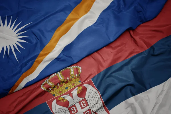 waving colorful flag of serbia and national flag of Marshall Islands .