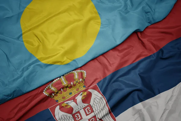 waving colorful flag of serbia and national flag of Palau .