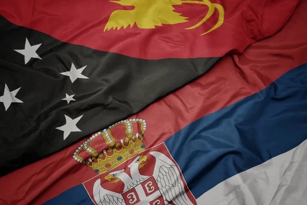 waving colorful flag of serbia and national flag of Papua New Guinea .