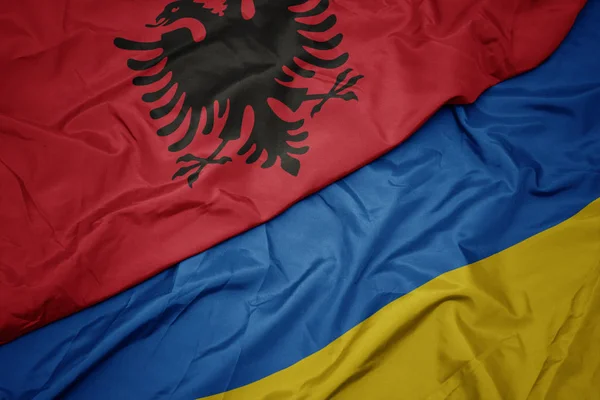 Waving colorful flag of ukraine and national flag of albania. — Stock Photo, Image