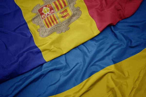 Agitant drapeau coloré de l'ukraine et drapeau national de l'andorre . — Photo