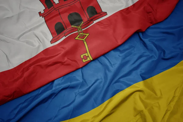 Размахивая красочным флагом Украины и национальным флагом Гибралтара . — стоковое фото