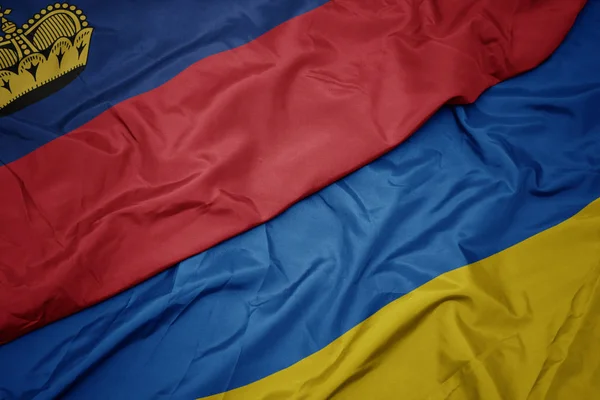 Acenando bandeira colorida de ucraniano e bandeira nacional de liechtenstein . — Fotografia de Stock