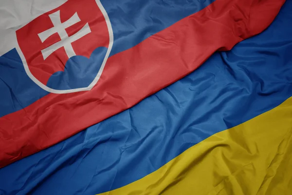 Acenando bandeira colorida da Ucrânia e bandeira nacional da Eslováquia . — Fotografia de Stock