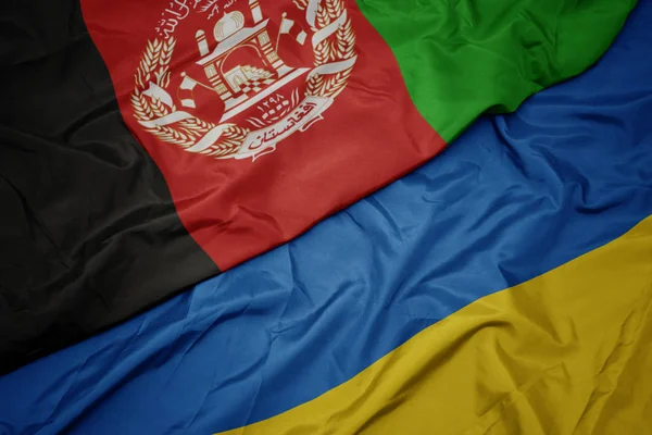 Ondeando colorida bandera de Ucrania y bandera nacional de Afganistán . — Foto de Stock