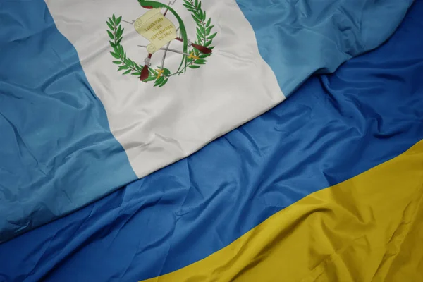 Waving colorful flag of ukraine and national flag of guatemala. — Stock fotografie