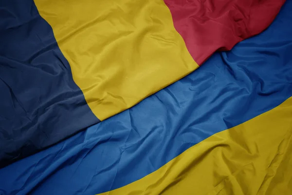Zwaaiende kleurrijke vlag van ukraïne en nationale vlag van chad. — Stockfoto