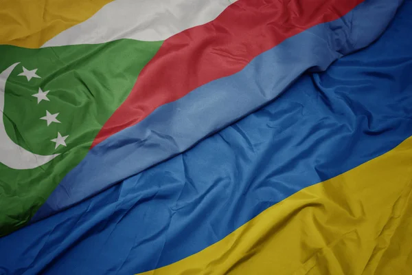Ondeando colorida bandera de Ucrania y bandera nacional de las comoras . — Foto de Stock