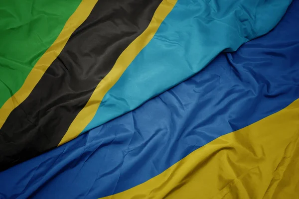 Ondeando colorida bandera de Ucrania y bandera nacional de Tanzania . —  Fotos de Stock