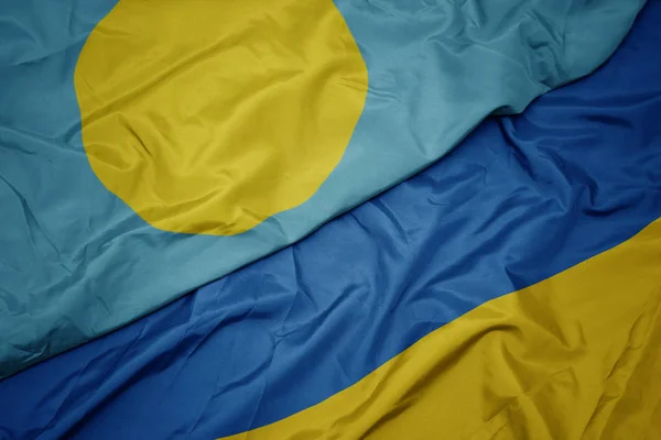 Waving colorful flag of ukraine and national flag of Palau . — Stock Photo, Image