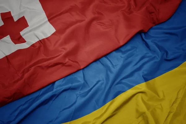 Waving colorful flag of ukraine and national flag of Tonga . — Stock Photo, Image