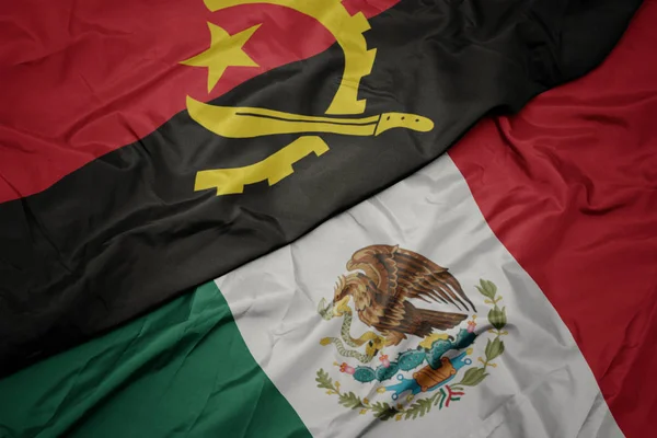 Waving colorful flag of mexico and national flag of angola. macro — Stock Photo, Image