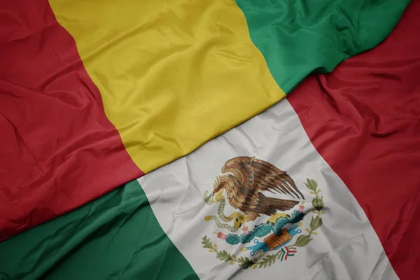 Waving colorful flag of mexico and national flag of guinea. macro — Stock Photo, Image