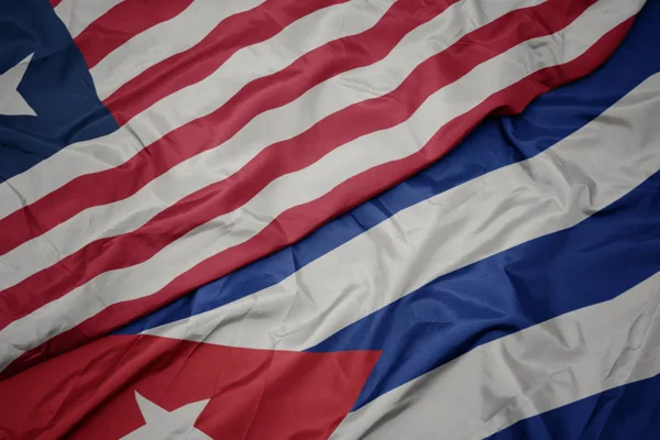 Agitant drapeau coloré de cuba et drapeau national de liberia . — Photo