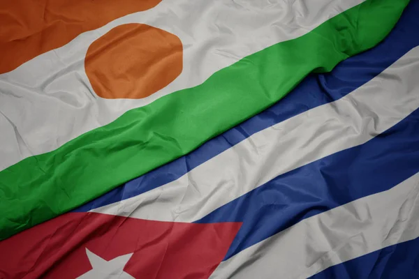 Agitant drapeau coloré de cuba et drapeau national de niger . — Photo