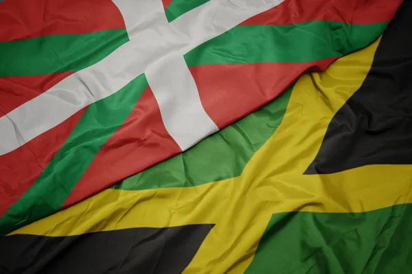 Ondeando colorida bandera de jamaica y bandera nacional del país vasco . — Foto de Stock