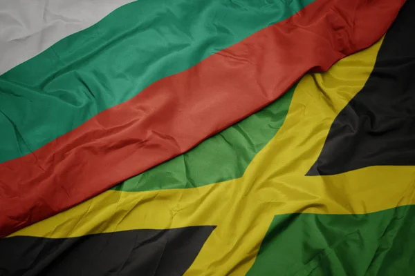 Agitant drapeau coloré de jamaïca et drapeau national de bulgarie . — Photo