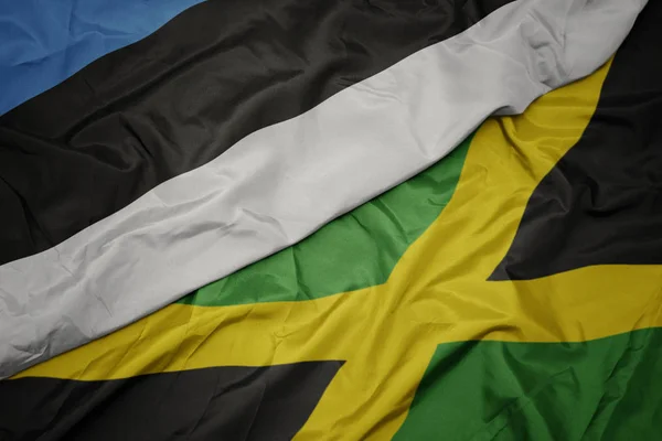 Ondeando colorida bandera de jamaica y bandera nacional de estonia . — Foto de Stock
