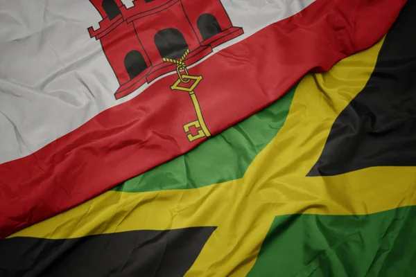 Ondeando colorida bandera de jamaica y bandera nacional de gibraltar . — Foto de Stock