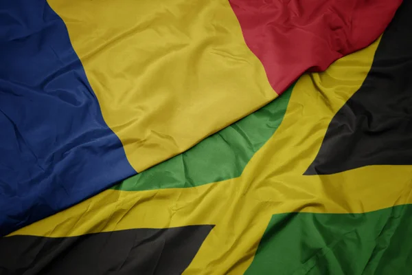 Ondeando colorida bandera de jamaica y bandera nacional de romania . — Foto de Stock