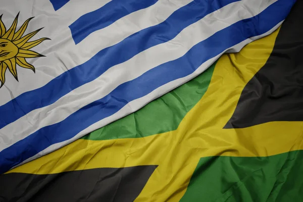 Waving colorful flag of jamaica and national flag of uruguay. — Stock Photo, Image