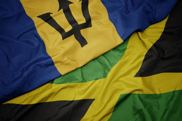 Machanie barwną flagą Jamajki i flagą narodową Barbadosu. — Zdjęcie stockowe