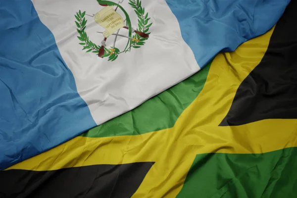Acenando bandeira colorida de jamaica e bandeira nacional de guatemala . — Fotografia de Stock