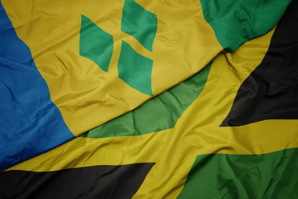 Lengetve színes zászló Jamaica és a nemzeti zászló szent Vincent és a gránátalmák. — Stock Fotó