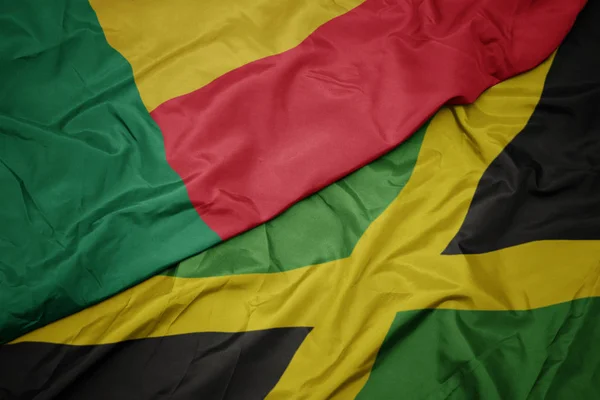 Ondeando colorida bandera de jamaica y bandera nacional de benin . — Foto de Stock