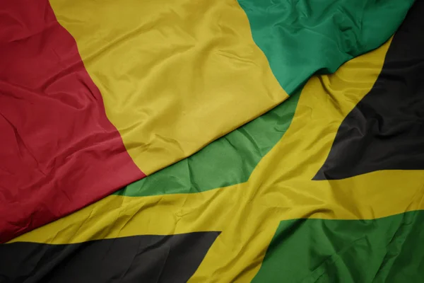 Ondeando colorida bandera de jamaica y bandera nacional de guinea . — Foto de Stock