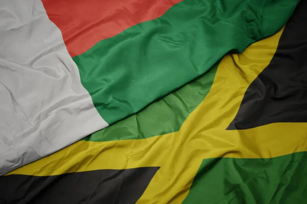 Ondeando colorida bandera de jamaica y bandera nacional de madagascar . — Foto de Stock