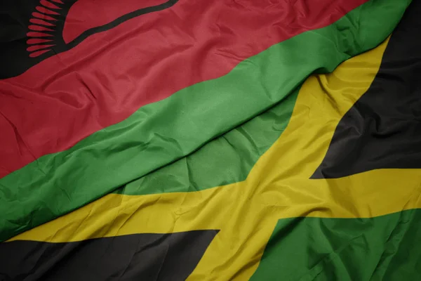 Agitant drapeau coloré de jamaica et drapeau national de malawi . — Photo