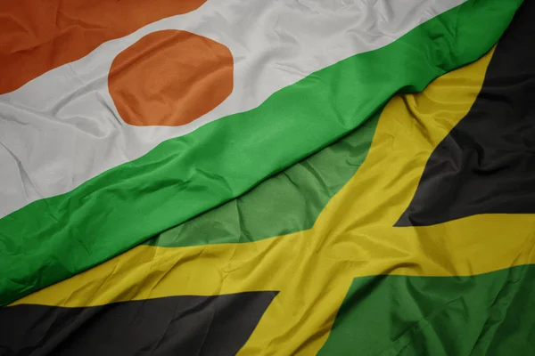 Ondeando colorida bandera de jamaica y bandera nacional de niger . — Foto de Stock